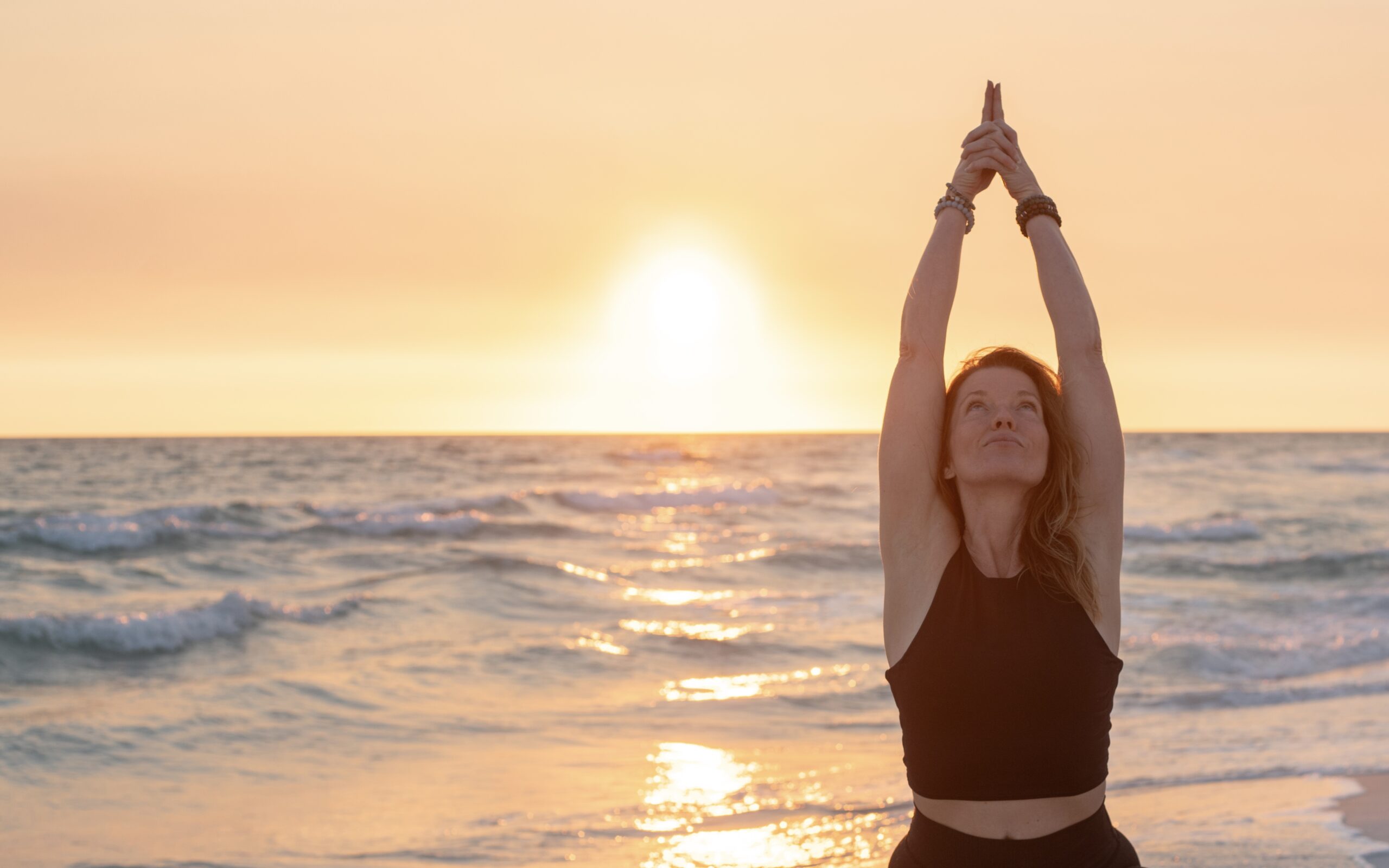 Steph in goddess pose at sunset on the beach